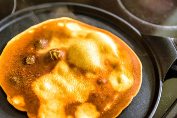 pancake frying pan with crepe pancake cooking on cooker in kitchen