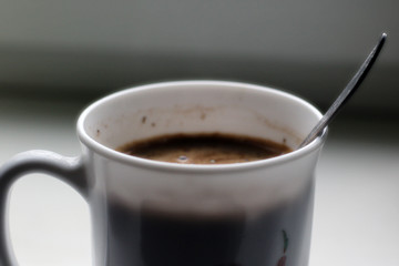 black coffee with foam in white mug with metal vintage spoon