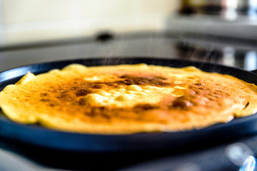 pancake frying pan with crepe pancake cooking on cooker in kitchen