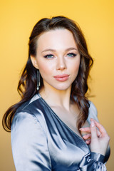 Fototapeta premium Portraits of a girl in an expensive evening dress. Beautiful girl in the Studio on a yellow background.