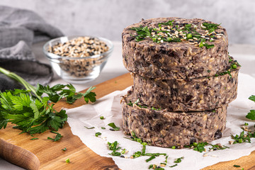 Raw veggie burger with black beans on wood countertop.