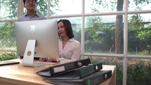 Businessman and woman making a conversation about the cooperate work on the environment of a modern green glass house office in front of a computer desktop. Media is in 4k resolution