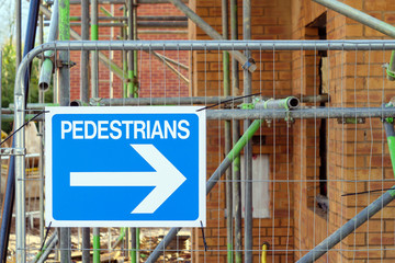 pedestrians directions lsign on fence over construction site in england uk