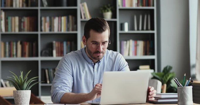 Excited business man checking email reading great news on laptop. Amazed male professional winner feeling happy receiving new job opportunity, reward bonus, celebrates financial market growth concept.