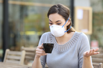 Confused girl holding a cup of coffee wearing mask