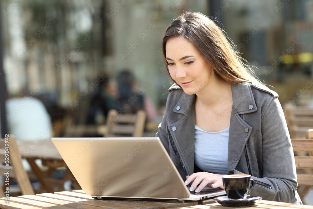 Poster young woman using her laptop on a restaurant terrace