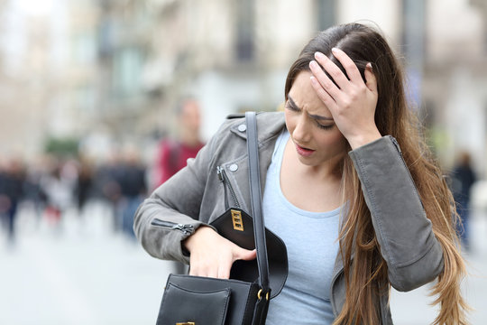 Worried woman looking inside her bag on street