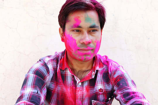 Closeup shot of Indian young man covered with multi color dry paint at Holi Festival.