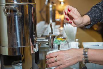 coffee espresso shot on a hand . Hand with fresh Black Coffee Pouring from Coffee machine . Professional espresso machine pouring strong looking fresh coffee into a neat cup .