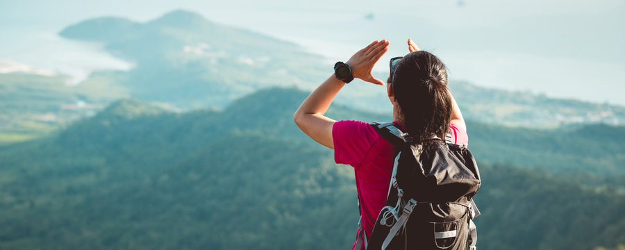 Young woman hiker yelling at mountain cliff edge