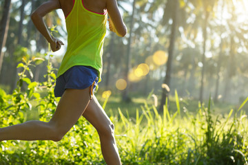 Young fitness woman running at morning tropical forest trail
