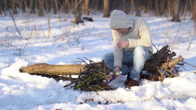 A man kindles a fire lighter in the winter forest