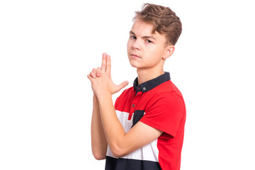Portrait of funny teen boy doing gun gesture getting ready to shoot. Caucasian young teenager showing raised gun gesture isolated on white background. Child holding symbolic gun. Emotions and signs.