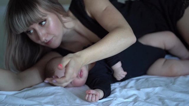 mom pulls out a pacifier from mouth sleeping baby