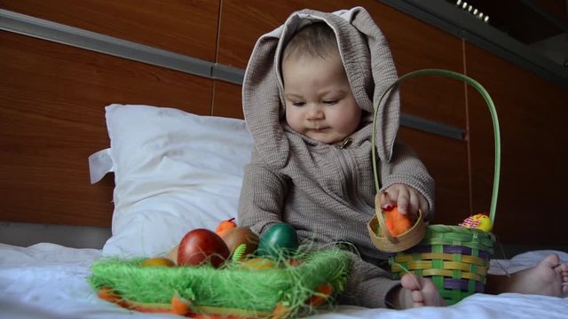 cute baby in bunny costume playing with the easter eggs. close up.