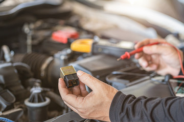 Professional mechanic man holding electrical component of car for testing and troubleshooting failure