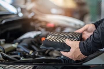 Professional mechanic man holding air filter of a car for repair and preventive maintenance car in...
