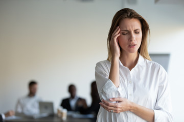Stressed young female office worker standing aside, feeling unhealthy unwell, suffering from high...