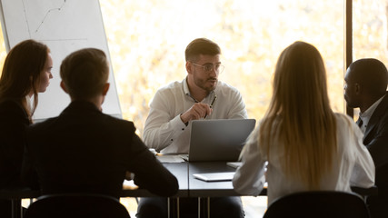 Concentrated confident male team leader holding brainstorming meeting with colleagues, discussing financial project results or negotiating business issues with partners investors clients coworkers.