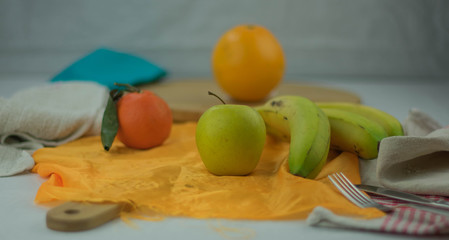 green apple on orange cloth accompanied by other fruits