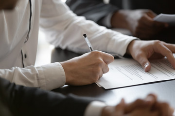 Close up young male employee manager customer hands signing paper contract after checking. Millennial investor client put signature at business agreement between partners. Editor making corrections. - obrazy, fototapety, plakaty