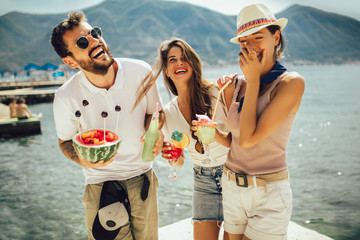 Friends at the beach drinking cocktails having fun on summer vacation