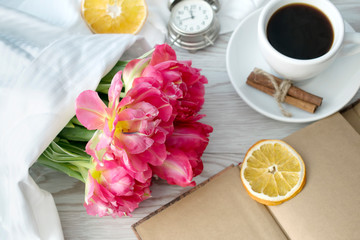 Greeting card with pink tulips and coffee on white wooden background. Copy space for text. Gift concept.