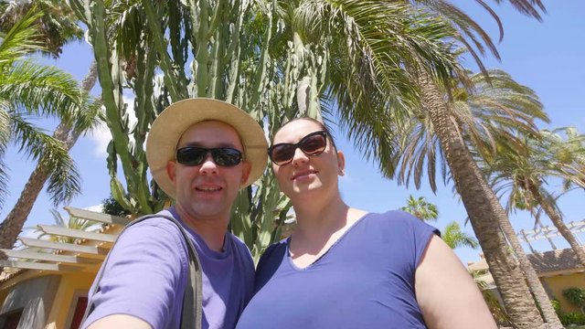 Happy couple taking a selfie and sending greetings in tropical resort in 4k slow motion 60fps