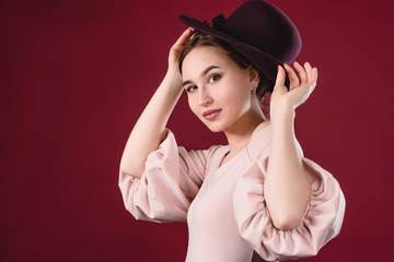 Beautiful young girl try on a hat on a red background