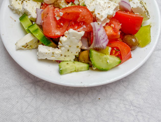 famous Greek salad plate with Feta goat cheese, tomatoes, cucumbers, olives, onions and olive oil partial view