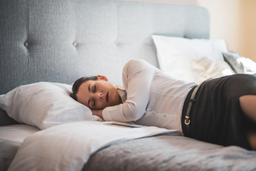 Tired businesswoman is sleeping dressed in hotel room.