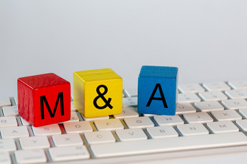 colorful blocks with the letters M&B which stand for Mergers and Acquisitions. The blocks are on a bright computer keyboard and isolated with white background