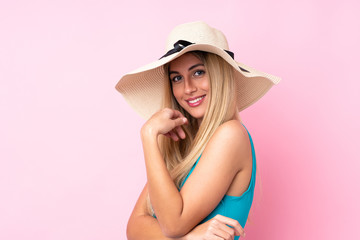 Young blonde Uruguayan woman in swimsuit in summer holidays over isolated pink background