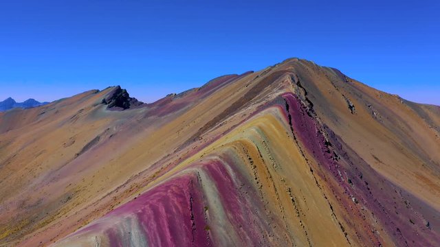 Aerial landscape of Rainbow Mountain Peak at  Vinicunca Valley. A mountain with intense red, yellow, orange, green and blue colors. Visitors on the watch point in a hilltop look them.