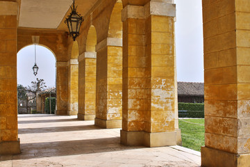 Yellow vintage colonnade with wrought iron lamps