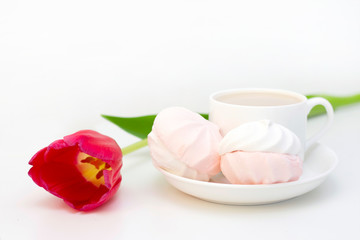 marshmallows, tea or coffee with milk and a tulip flower. on a light background. Romantic spring morning. delicate breakfast, breakfast in bed. for the beloved. Surprise.