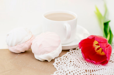 marshmallows, tea or coffee with milk and a tulip flower. on a light background. Romantic spring morning. delicate breakfast, breakfast in bed. for the beloved. Surprise.