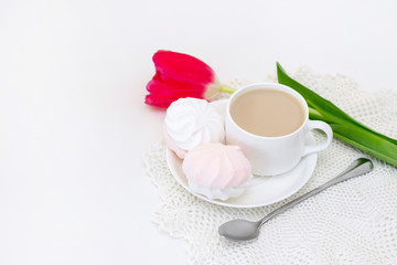 Fototapeta na wymiar marshmallows, tea or coffee with milk and a tulip flower. on a light background. Romantic spring morning. delicate breakfast, breakfast in bed. for the beloved. Surprise.