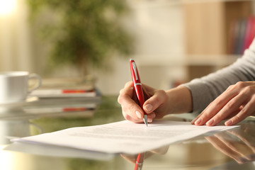 Woman signing document with pen on a desk at home - obrazy, fototapety, plakaty