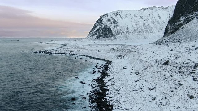 aerial view of snow covered mountain landscape eggum beach lofoten drone flying along the sea coast