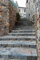 Fototapeta na wymiar Tossa de Mar, Spain, August 2018. Narrow street in the old fortress as a staircase to the fortress wall.
