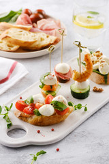 Traditional spanish tapas appetizer. Pinchos with mozzarella, cucumbers, shrimp and prosciutto.