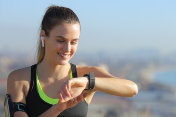 Happy runner with earbuds checking smart watch