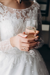 Vertical image of bride hand with perfect design manicure holding glass of fresh champagne. Bride morning. Female beauty and elegance.
