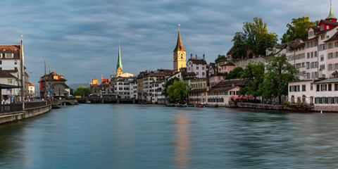 Panoramic view of Fraumunster and St Peter church with reflections in river Limmat at sunrise, Old Town of Zurich, the largest city in Switzerland