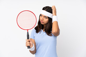 Young badminton player woman over isolated white background having doubts while scratching head