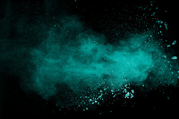 Obraz na płótnie Canvas Abstract splash of green colored powder on black background.Green powder explosion.