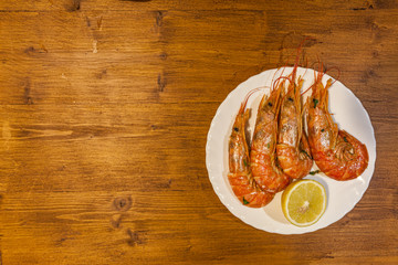 Dish with prawns and lemon on wooden background. Concept: cuisine based on fish