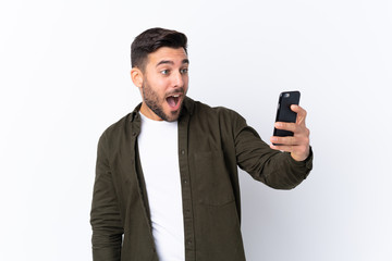 Naklejka premium Young handsome man with beard over isolated white background making a selfie
