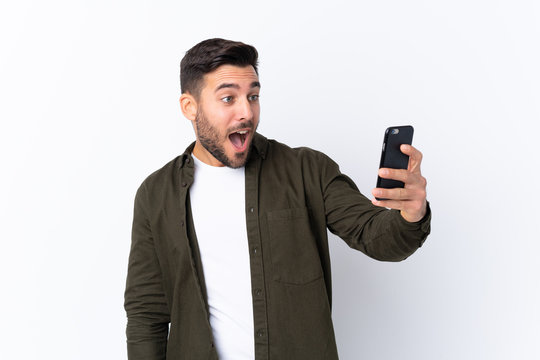 Young handsome man with beard over isolated white background making a selfie